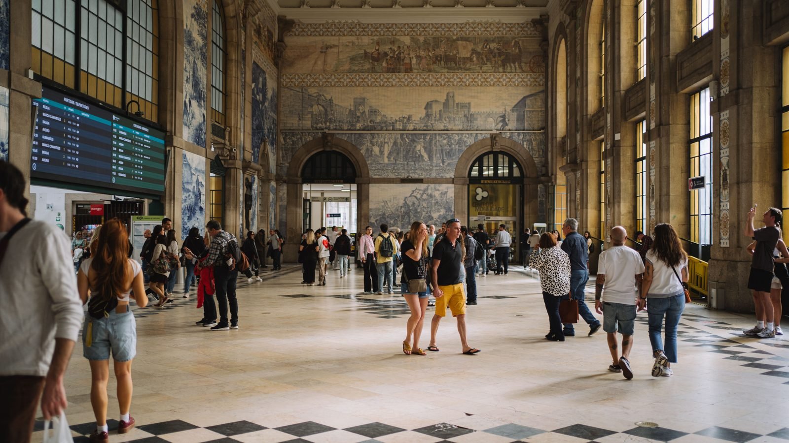 People exploring the tile-adorned hall of Sao Bento train station in Porto.