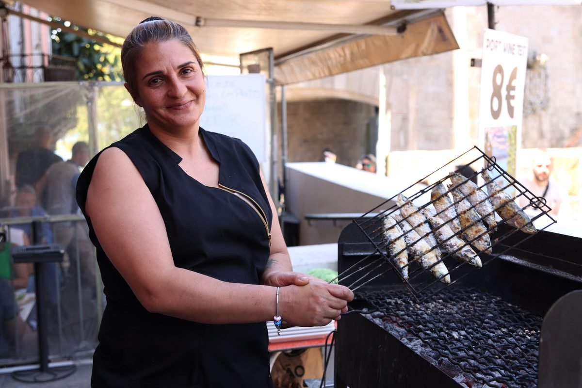 Female chef grilling fresh fish outdoors at a food stall in Porto.