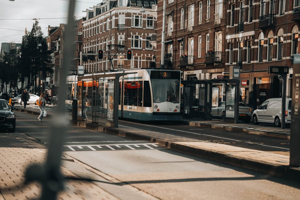 A blue and white GVB tram on a street in Amsterdam.