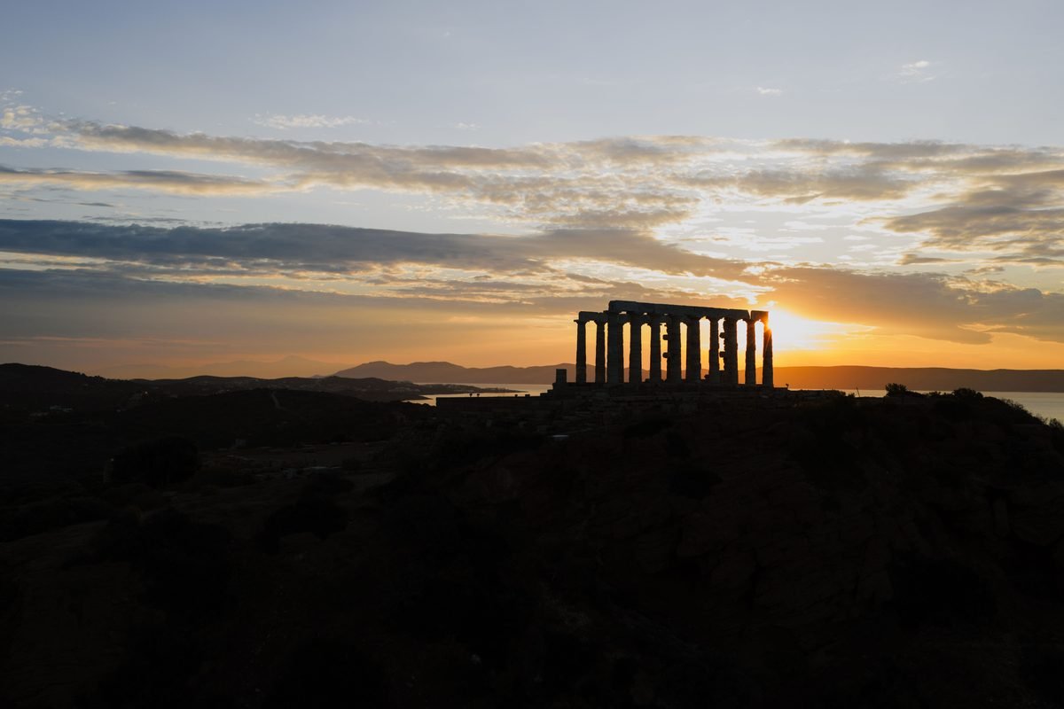 Ancient temple ruins on a hill overlooking the sea at sunset