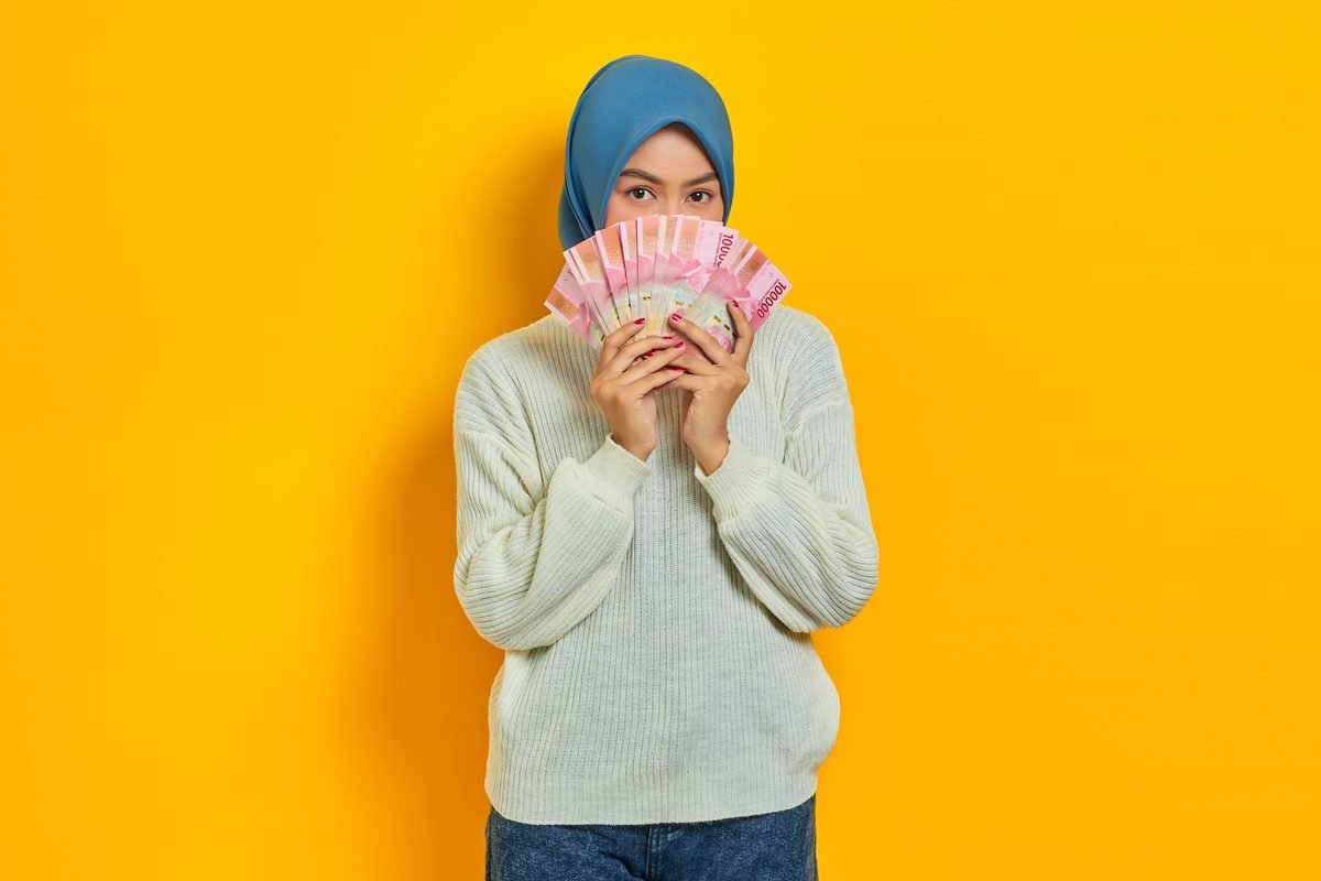 Woman holding Indonesian Rupiah banknotes covering her face