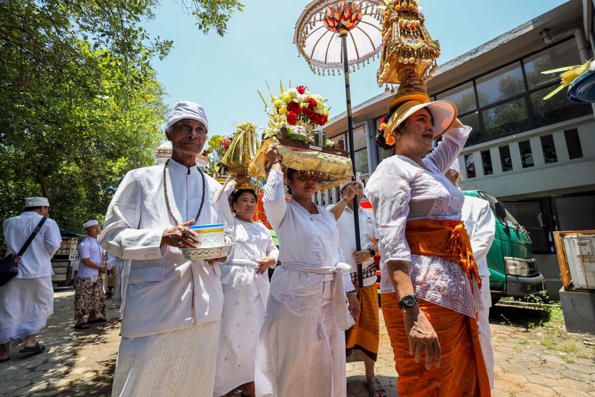Balinese people in traditional white attire participating in a ceremony