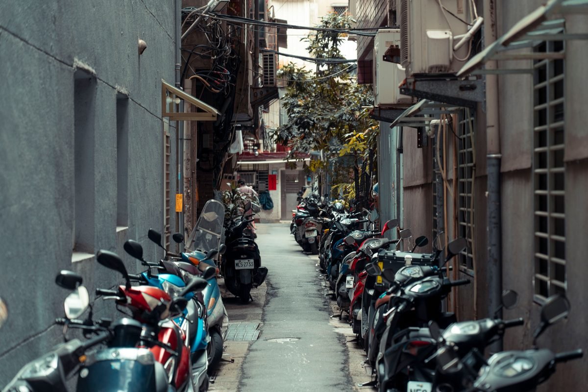 Narrow alleyway lined with parked scooters on both sides