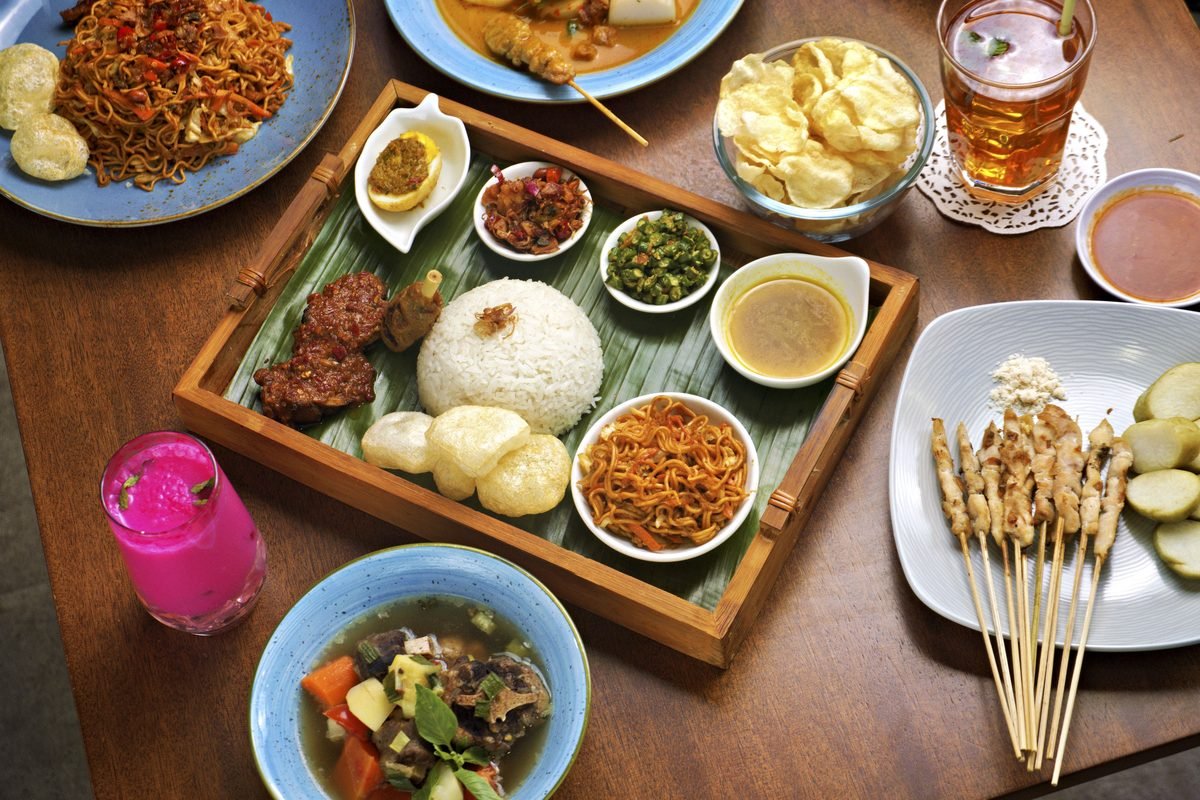 Indonesian meal featuring Nasi Campur and various side dishes on a table