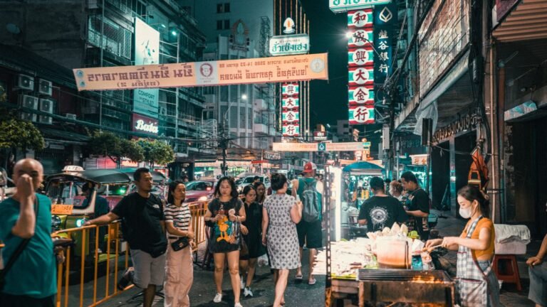 Vibrant night street market in Bangkok with neon signs, food stalls, and bustling crowds