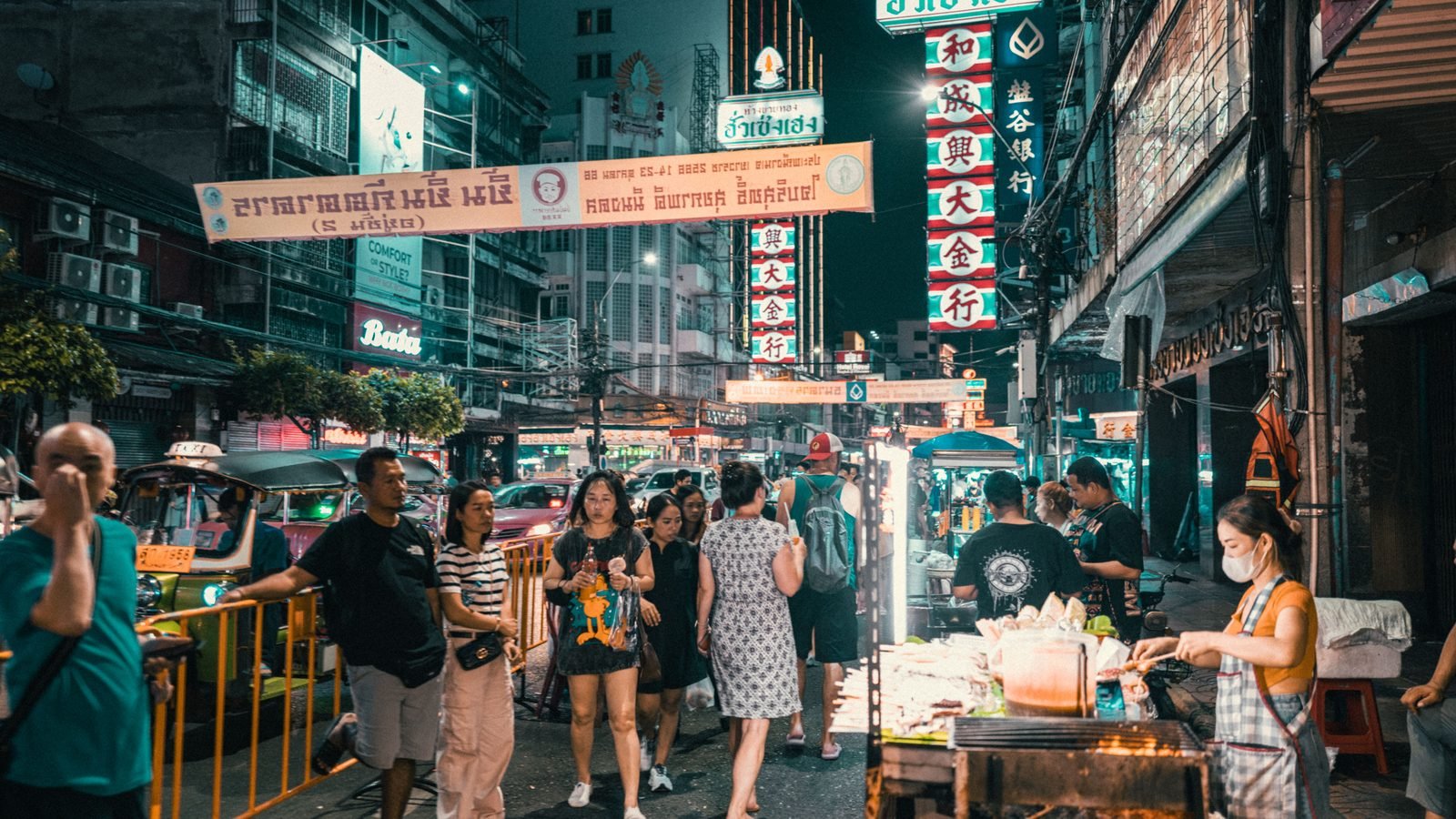 Vibrant night street market in Bangkok with neon signs, food stalls, and bustling crowds