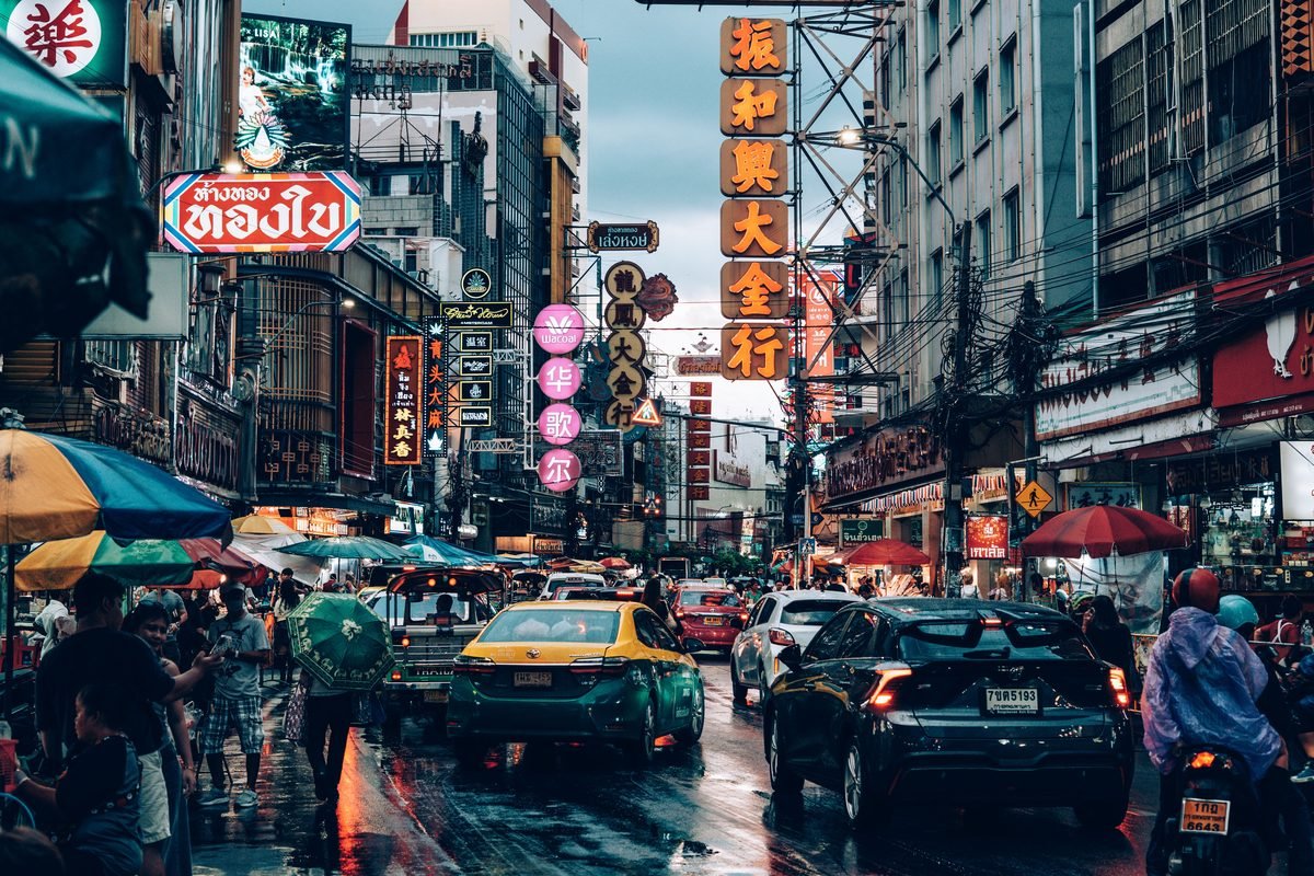 Busy Bangkok night market street scene with neon signs and traffic
