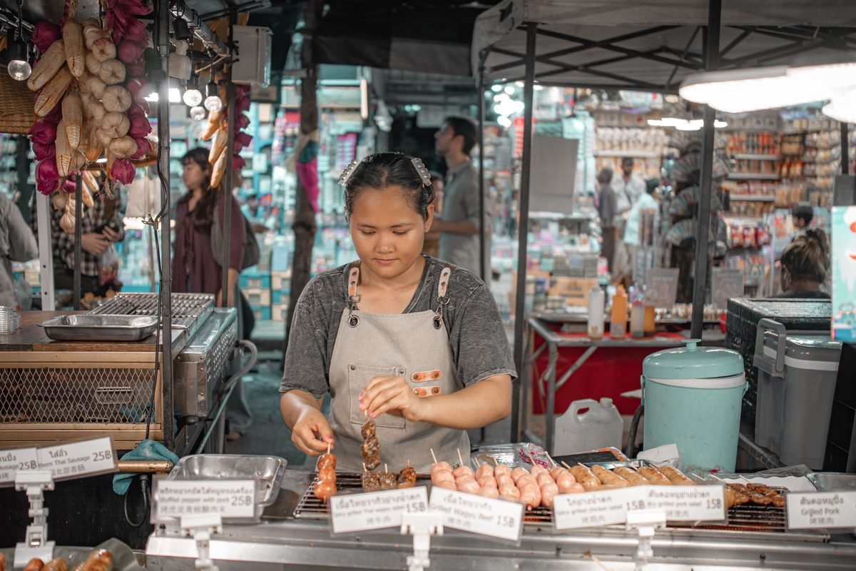 Vendor grilling skewers at a market stall
