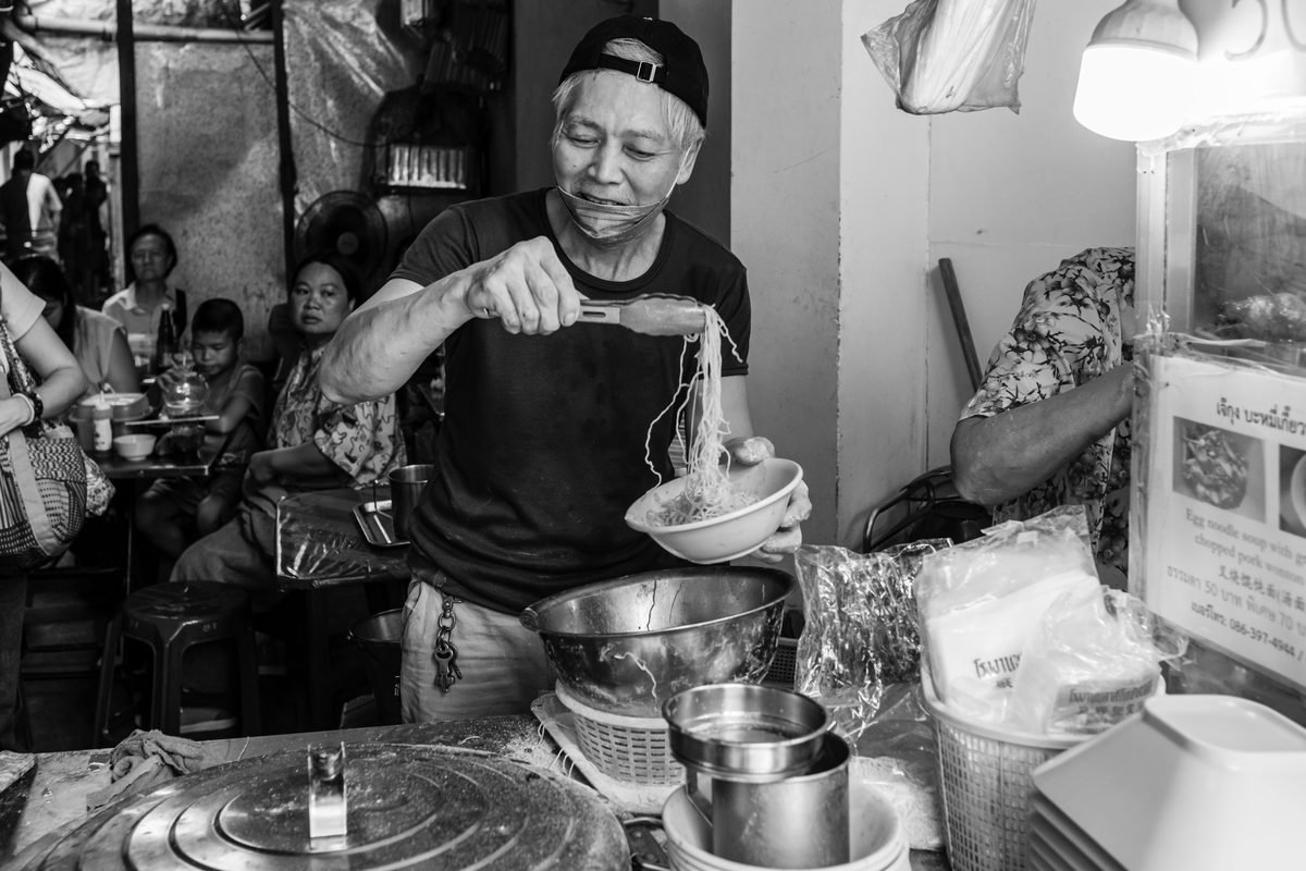 Black and white photo of a vendor preparing noodles