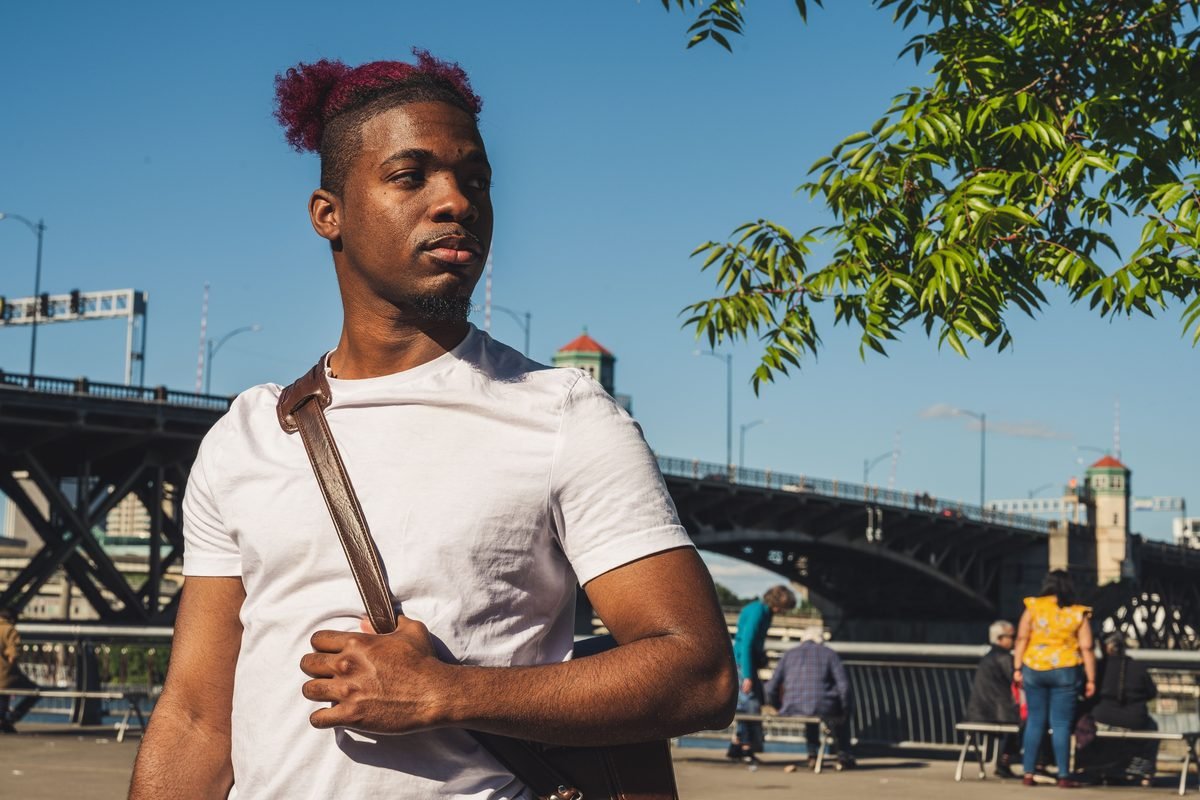 Young traveler wearing a secure crossbody bag outdoors near a city bridge.