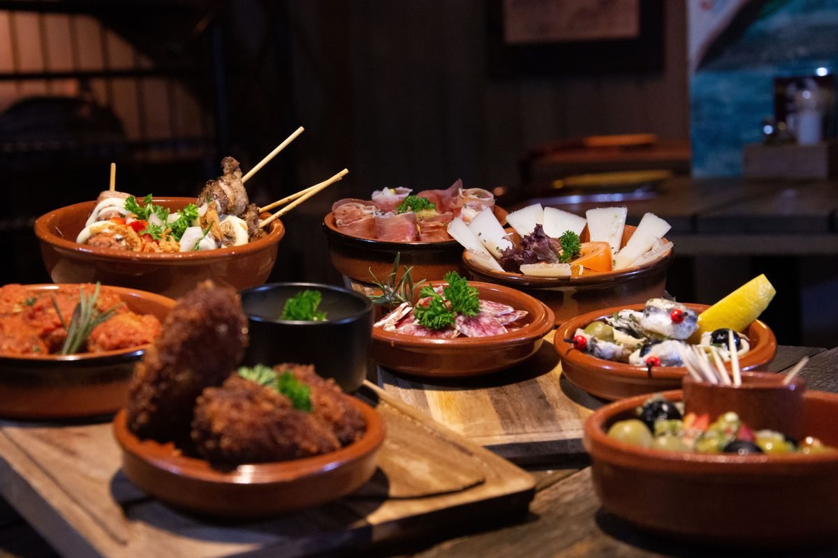 Selection of traditional Spanish tapas dishes arranged in clay bowls on a table.