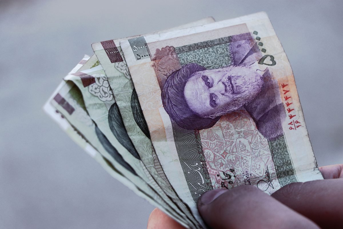 Detailed view of Iranian rial banknotes held in hand, illustrating finance and economy.