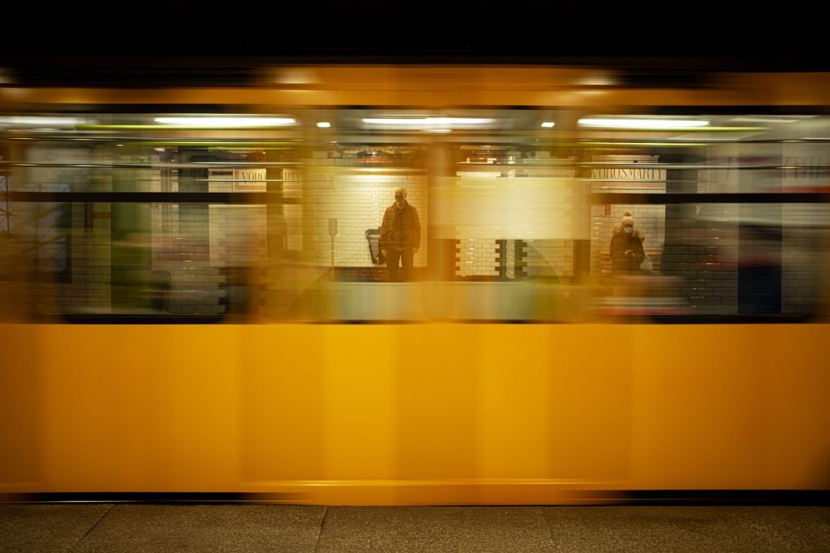 Yellow subway train moving through an underground station