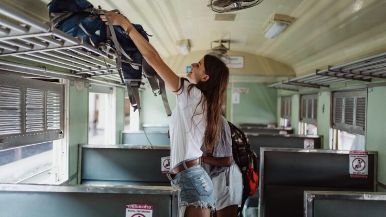 Woman placing backpack on a luggage rack inside a train carriage