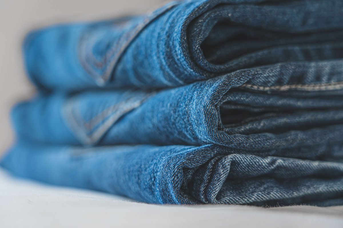 Detailed close-up image of a neat stack of folded blue denim jeans