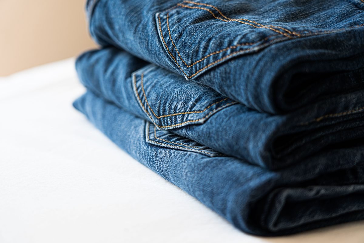 Stack of neatly folded blue denim jeans highlighting stitching details
