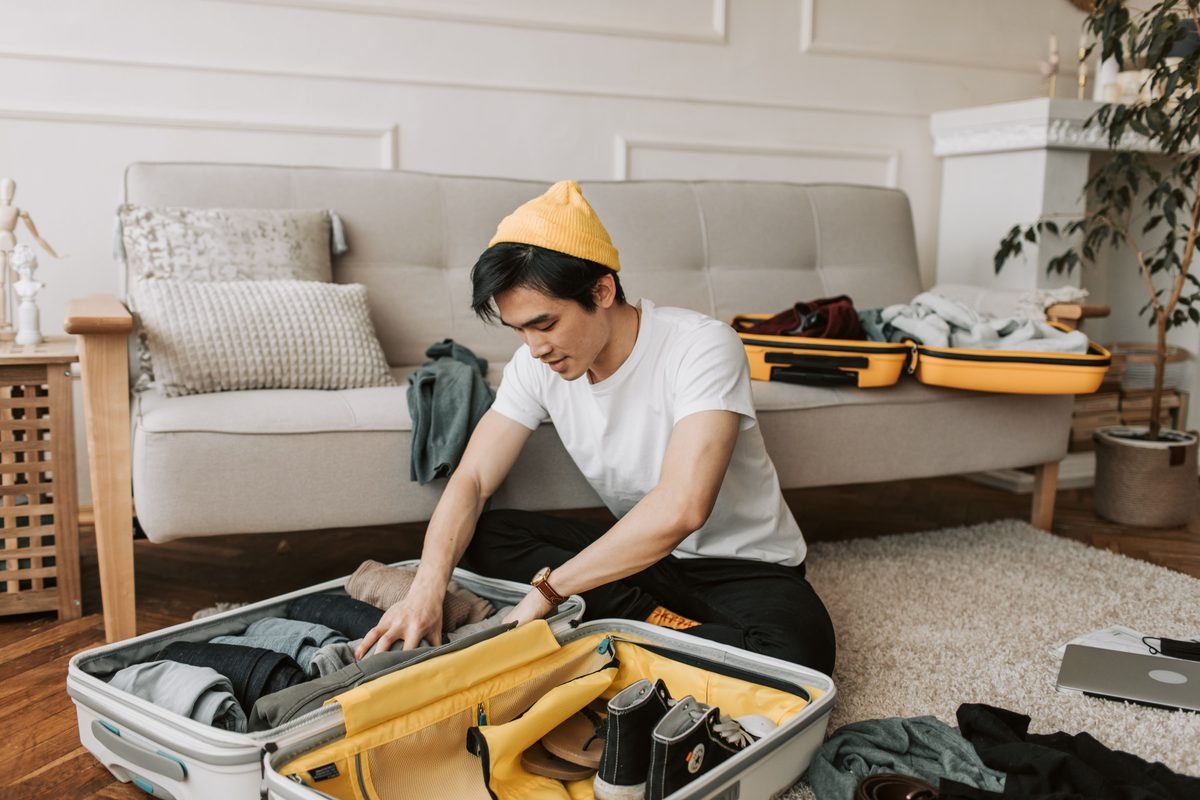 Young man organizing clothes in a suitcase in a cozy living room