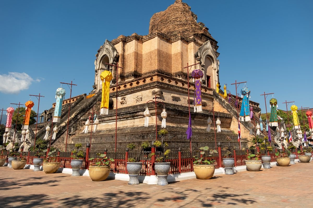 Weathered brick stupa of Wat Chedi Luang with colorful banners in Chiang Mai