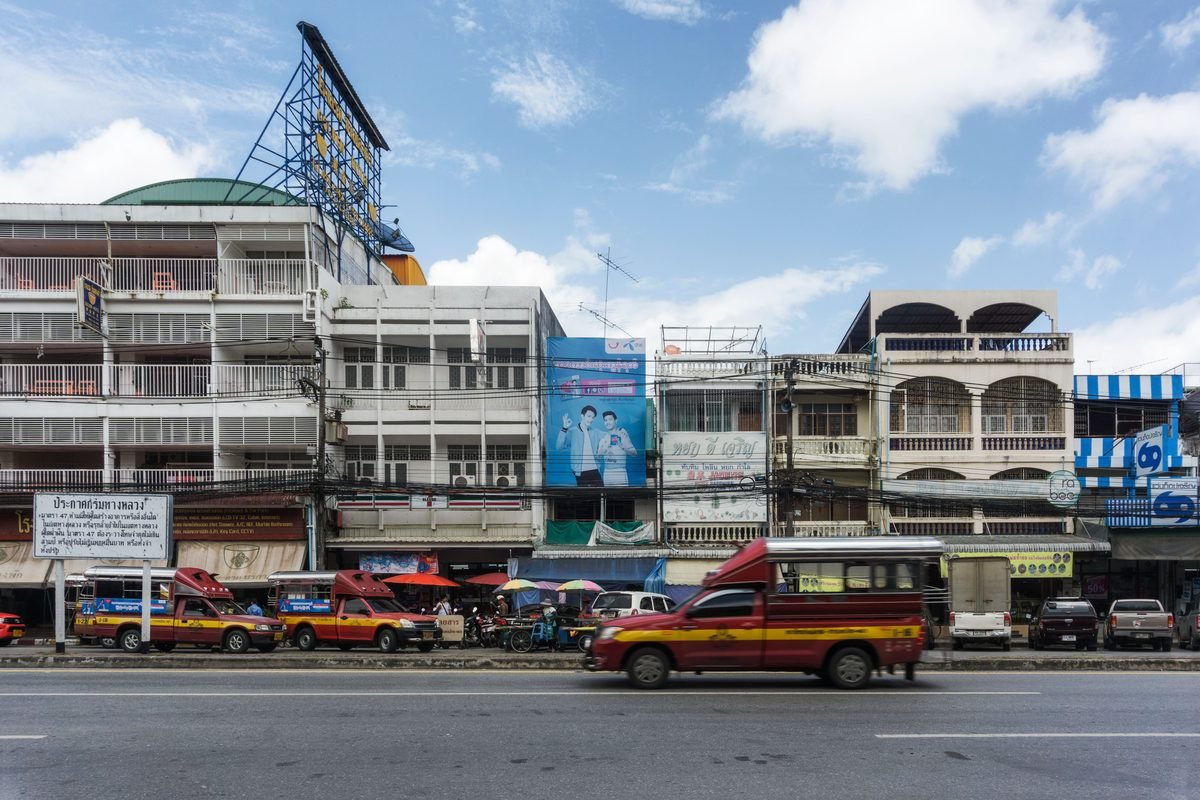 Red songthaew taxis driving on a city street in Chiang Mai