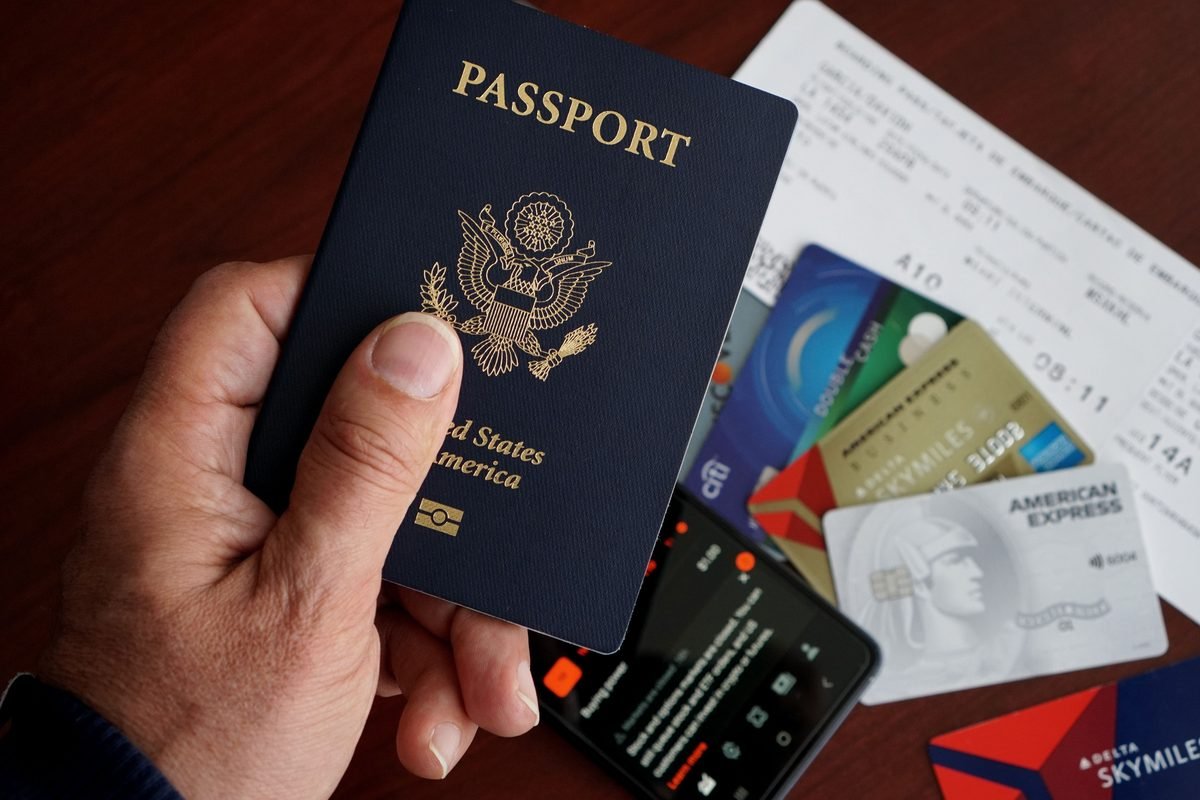 A passport held with boarding passes and credit cards on a table.