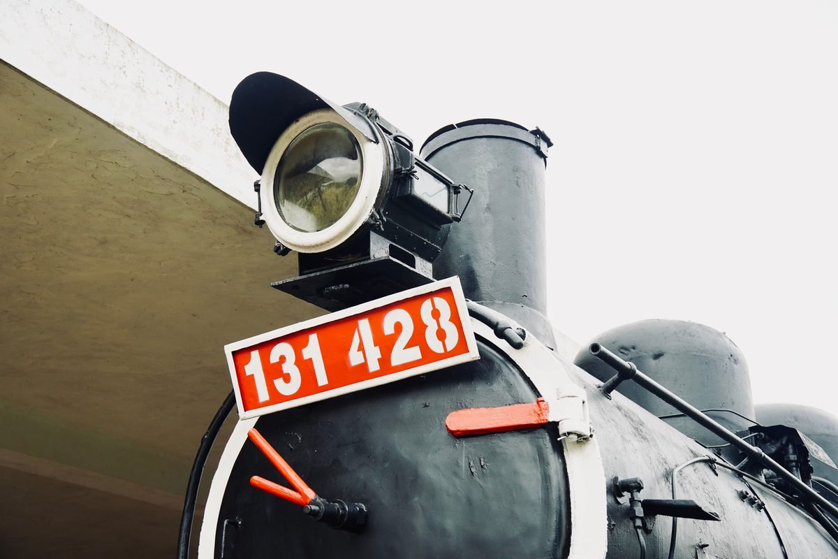 Close-up shot of an old steam locomotive front with identification plate.