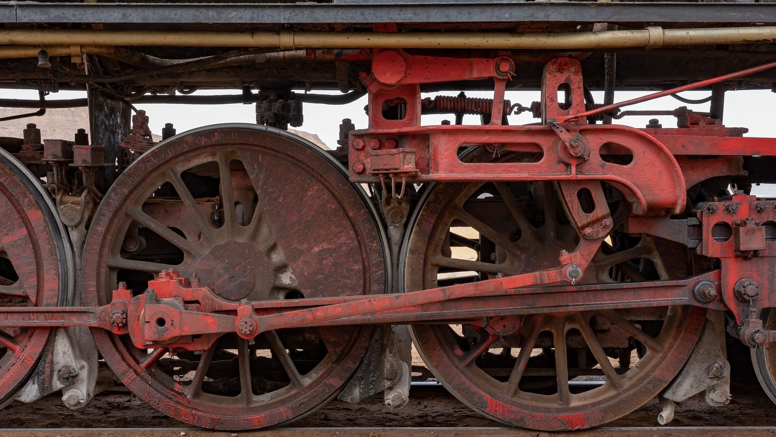 Detailed shot of large red vintage locomotive wheels and metalwork.