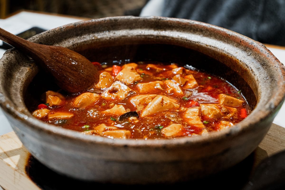 Close-up of a flavorful stew simmering in a rustic pot with a wooden spoon.