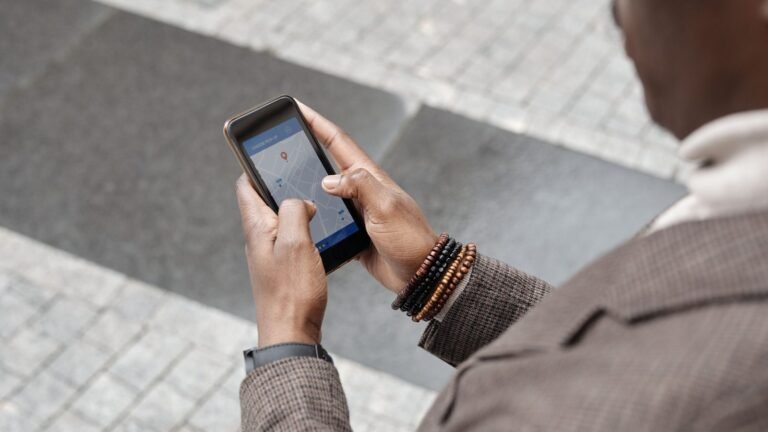 A person using a smartphone with a navigation map on an urban street.