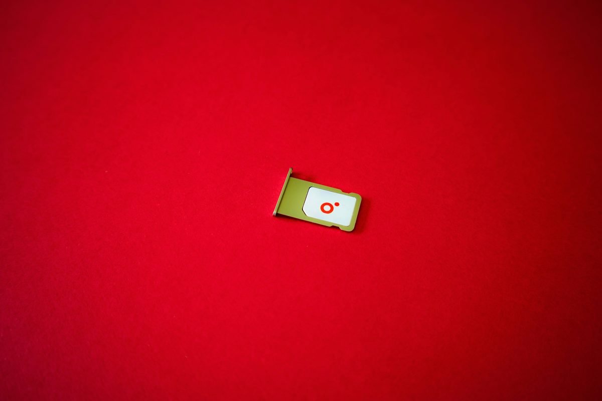 SIM card tray lying on a vibrant red background.