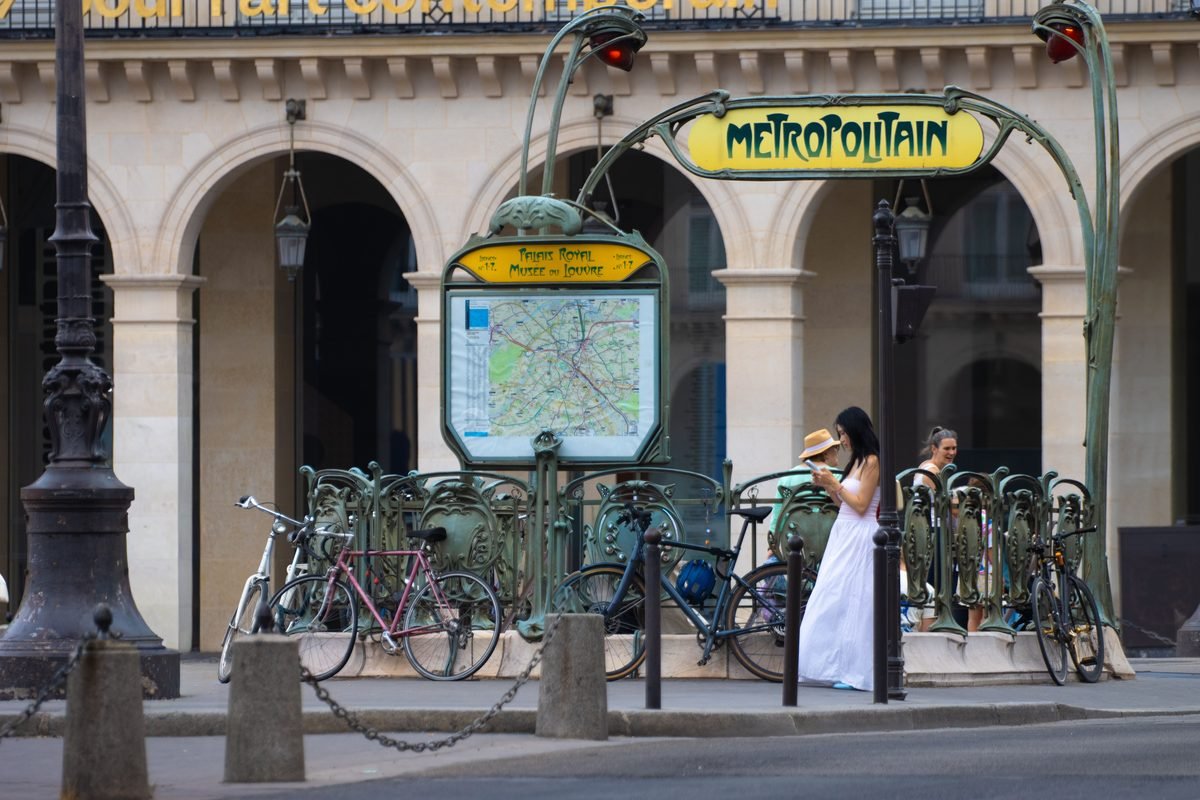 Busy Paris Metro entrance with pedestrians and bicycles.
