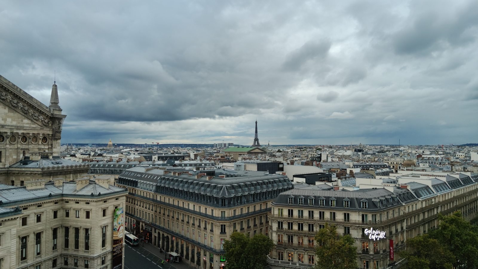Panoramic view of Paris showing the Eiffel Tower under cloudy skies.
