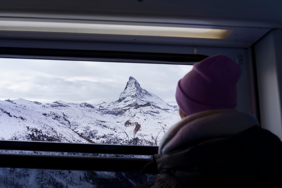 Snowy mountain peak viewed through a passenger train window.