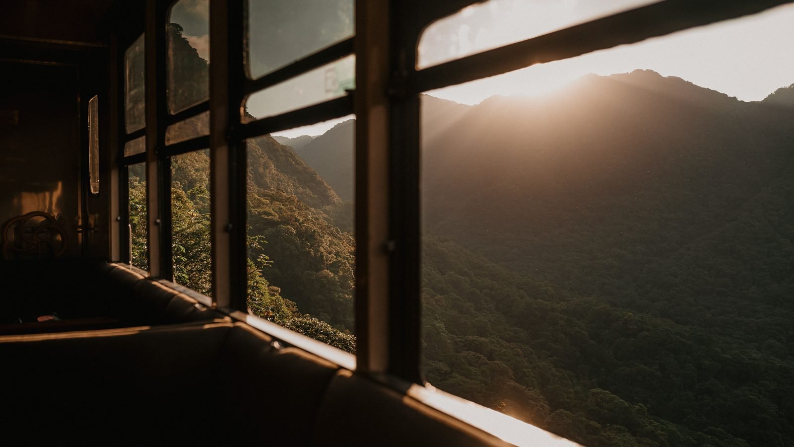 Mountain landscape framed by vintage train windows at sunset.