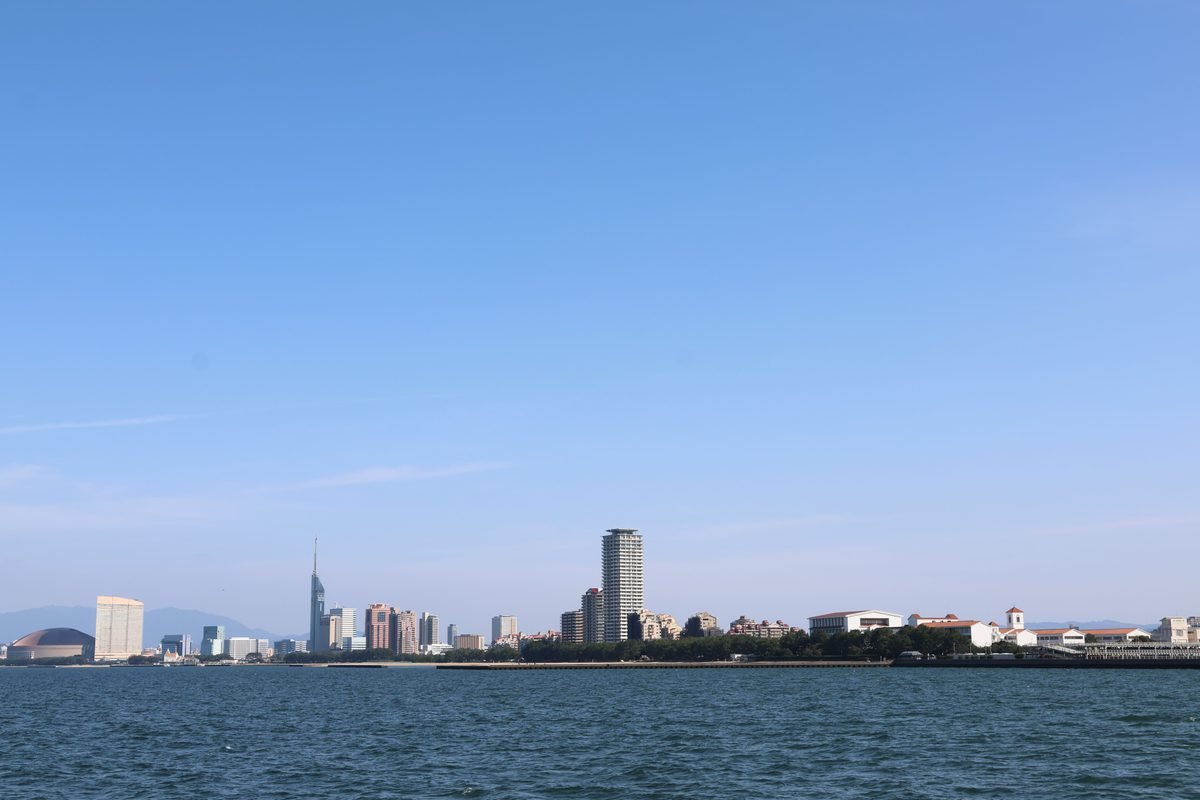 Fukuoka City skyline along the waterfront under a clear sky.