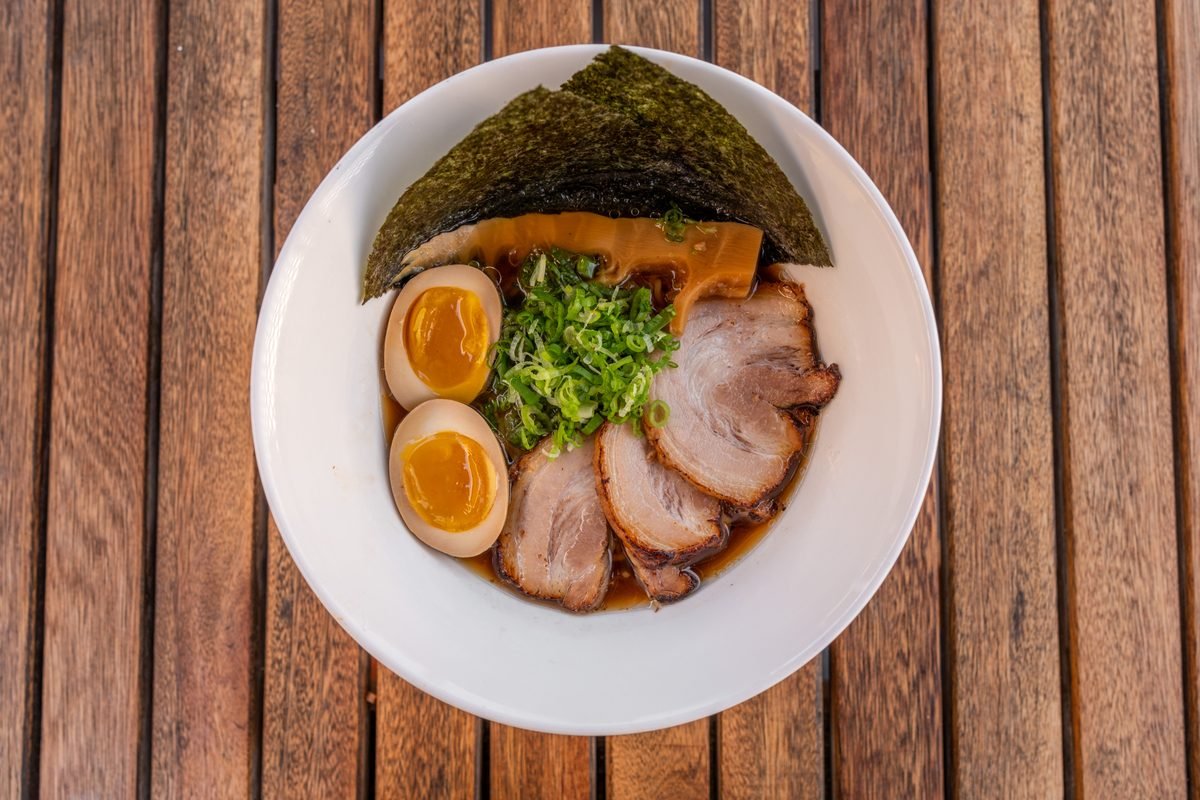 Shoyu ramen bowl with chashu and nori on a wooden table.