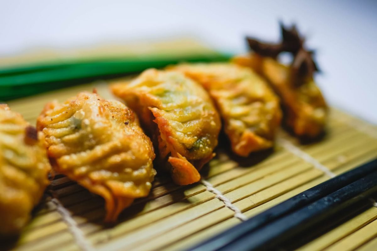 Fried gyoza dumplings arranged on a bamboo mat.