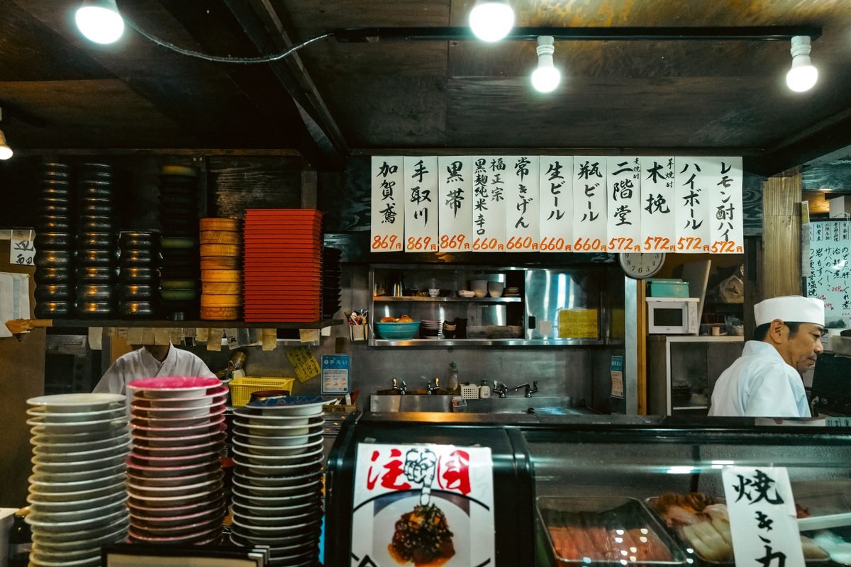 Interior of a traditional Japanese restaurant with menu boards and chef.