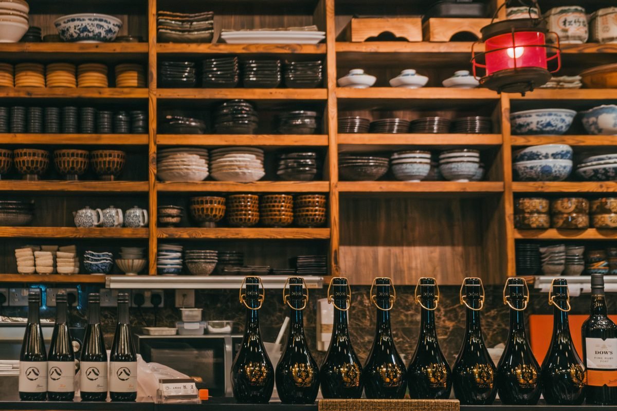 Rustic kitchen shelves with organized ceramic bowls and bottles.