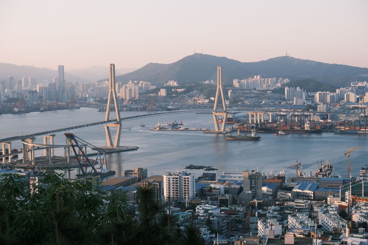 Scenic view of Busan harbor and cityscape with cable-stayed bridge at sunrise