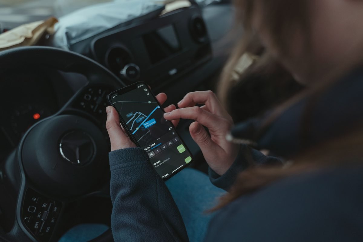 Person using a GPS navigation app on a smartphone inside a car