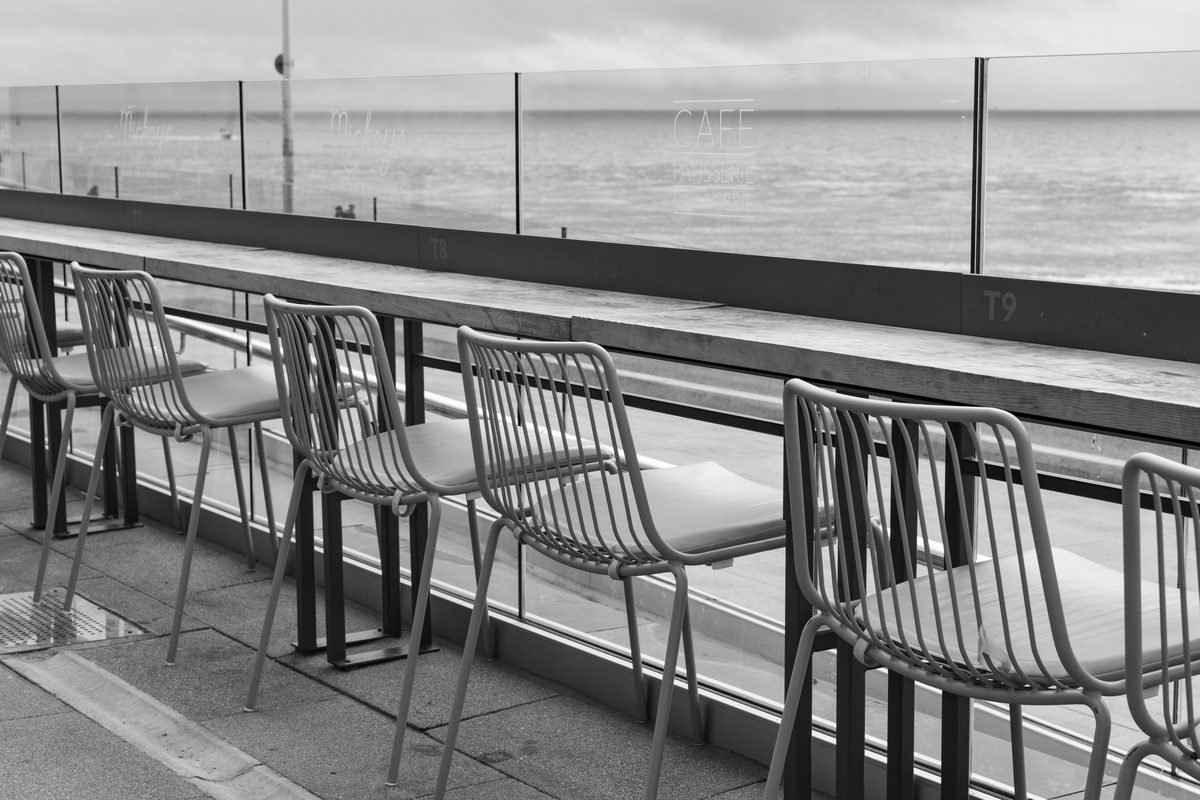 Empty seaside cafe chairs facing the ocean