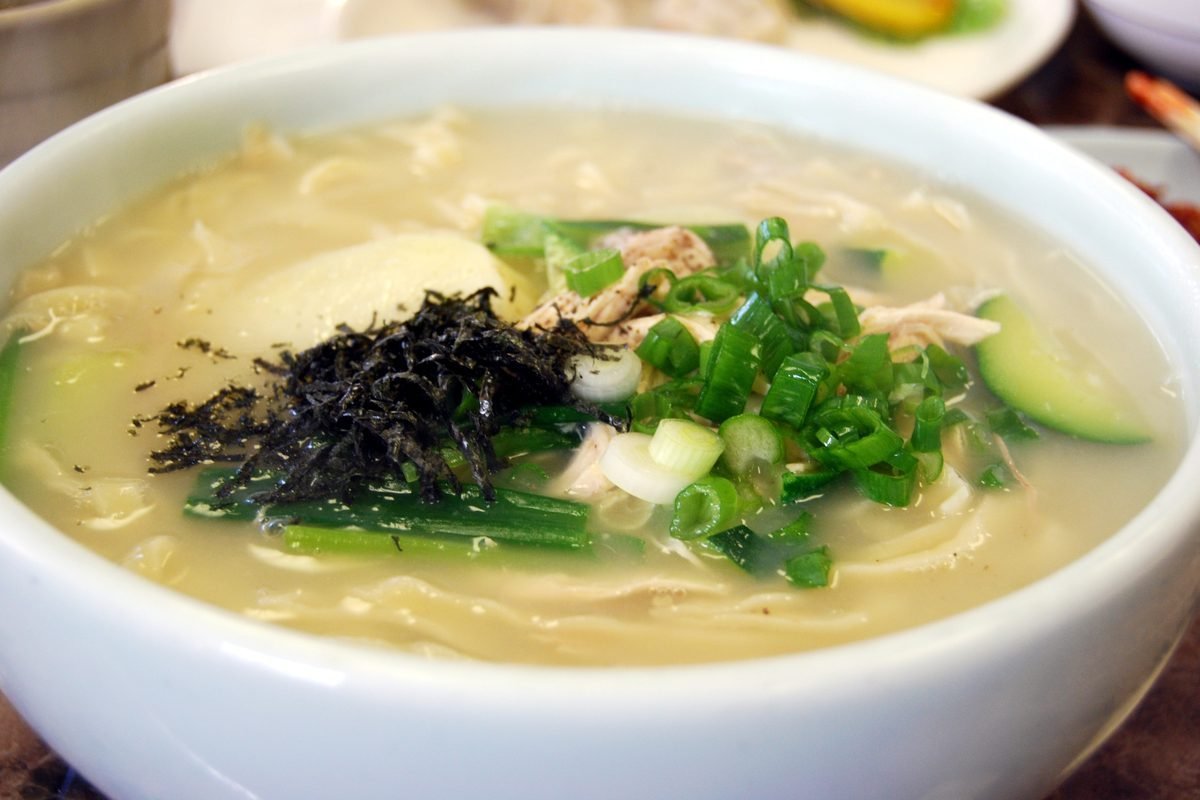 Bowl of kalguksu, Korean knife-cut noodle soup, topped with seaweed and scallions