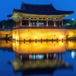 Illuminated wooden pavilion reflecting perfectly on the dark water of Wolji Pond at dusk in Gyeongju