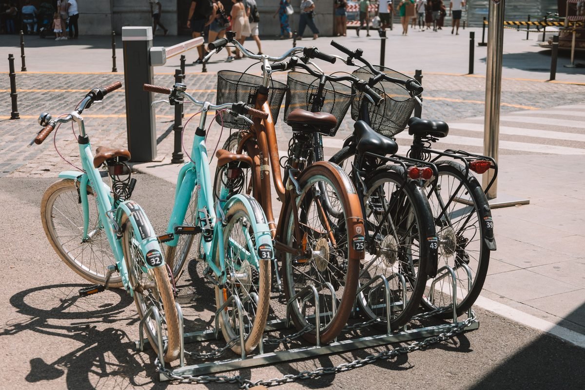 Bicycles parked neatly in a rack on a sunny paved street