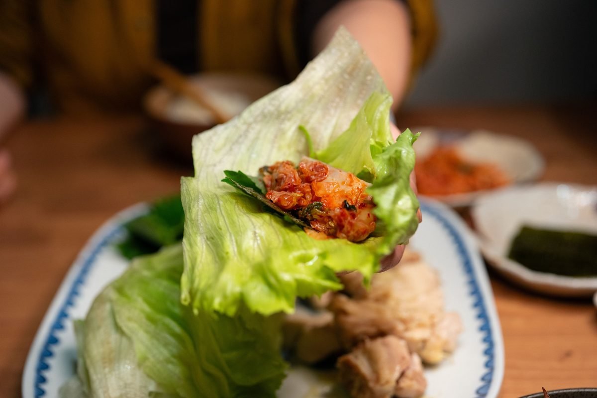 Close-up of a fresh Korean lettuce wrap filled with spicy kimchi
