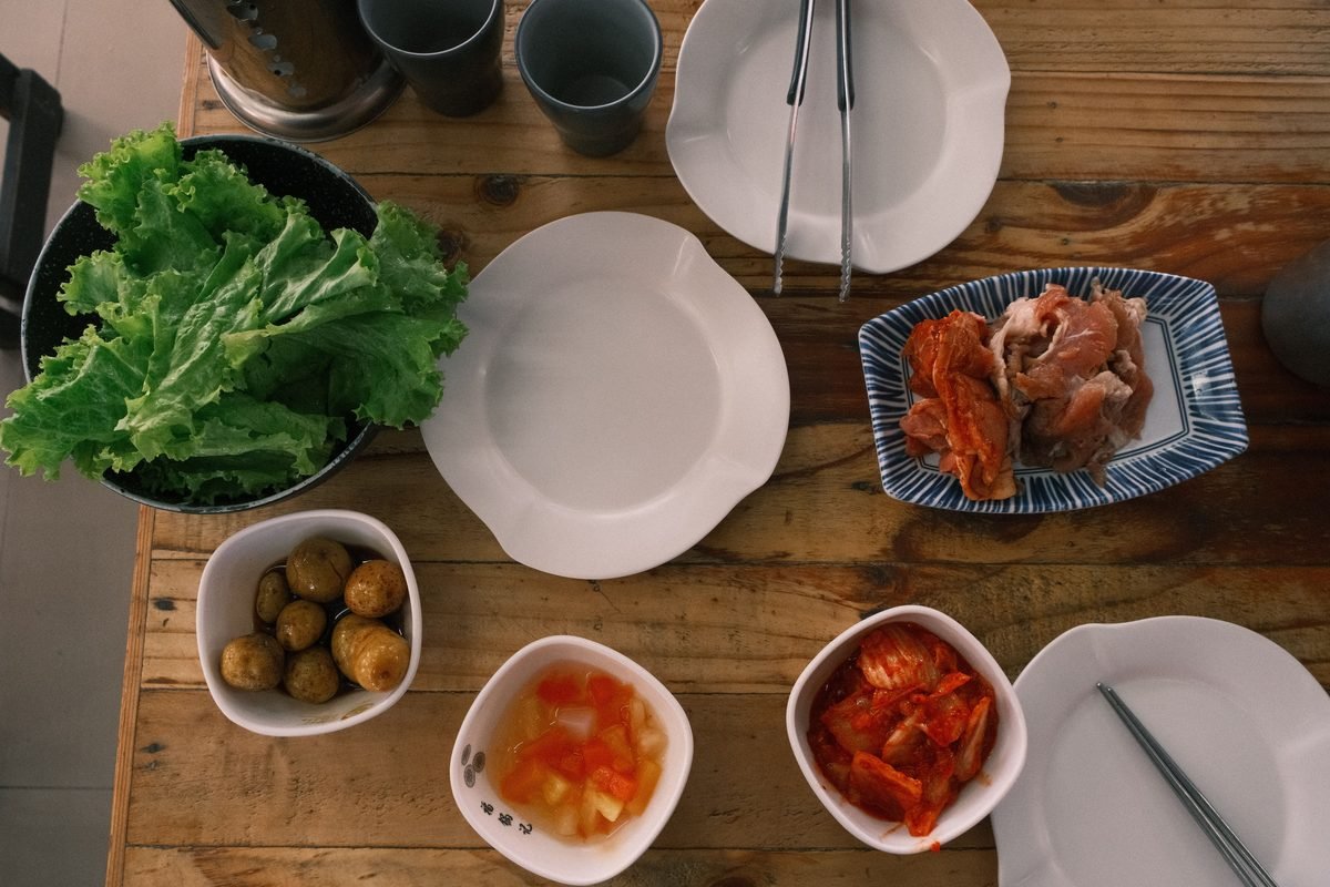 Overhead view of a traditional Korean meal spread with vegetables and side dishes