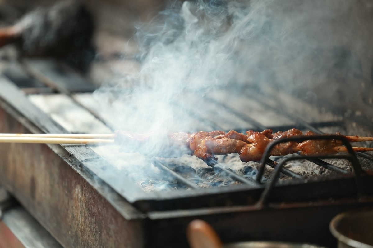 Close-up of meat skewers smoking on a charcoal grill