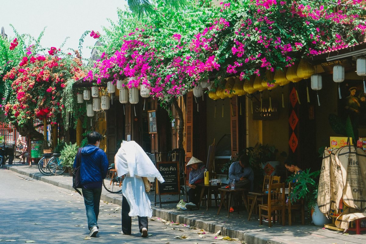 Yellow heritage building draped in pink bougainvillea in Hoi An