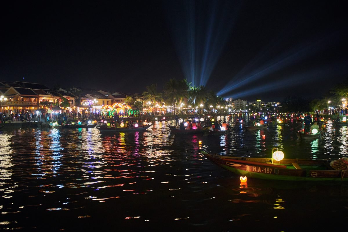 Tourists walking along lantern-lit street in Hoi An at twilight