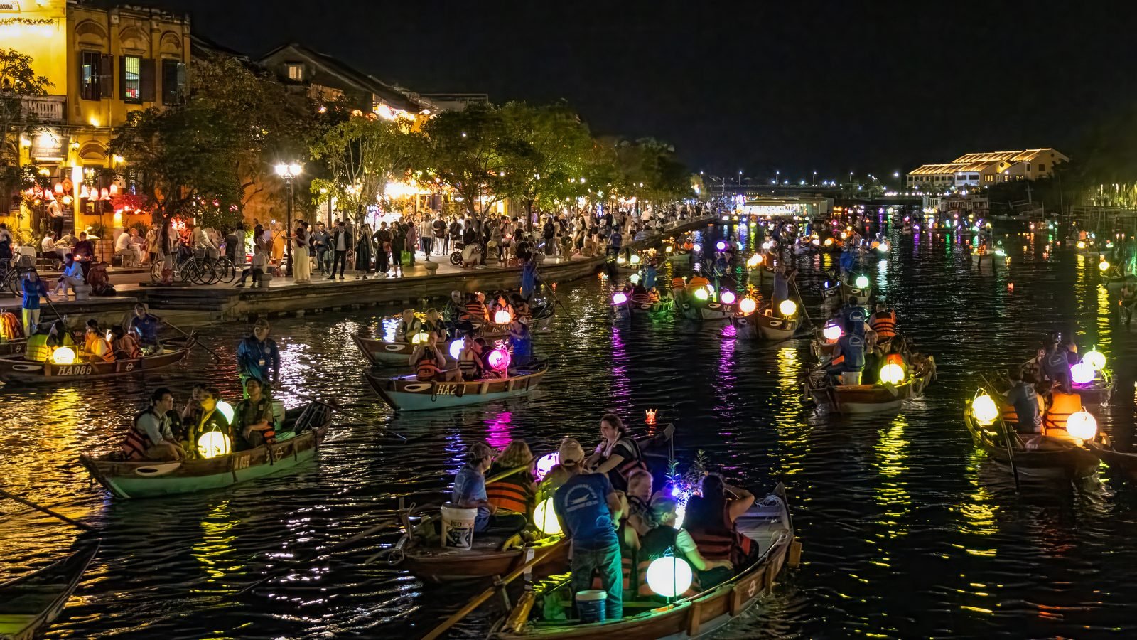 Boats with glowing lanterns on the river in Hoi An, Vietnam at twilight.